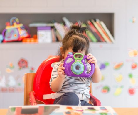 girl holding purple and green camera toy