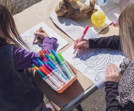 two young girls sitting at a table with markers and crayons