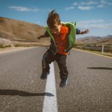 a young boy is jumping in the air on a road