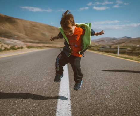 a young boy is jumping in the air on a road